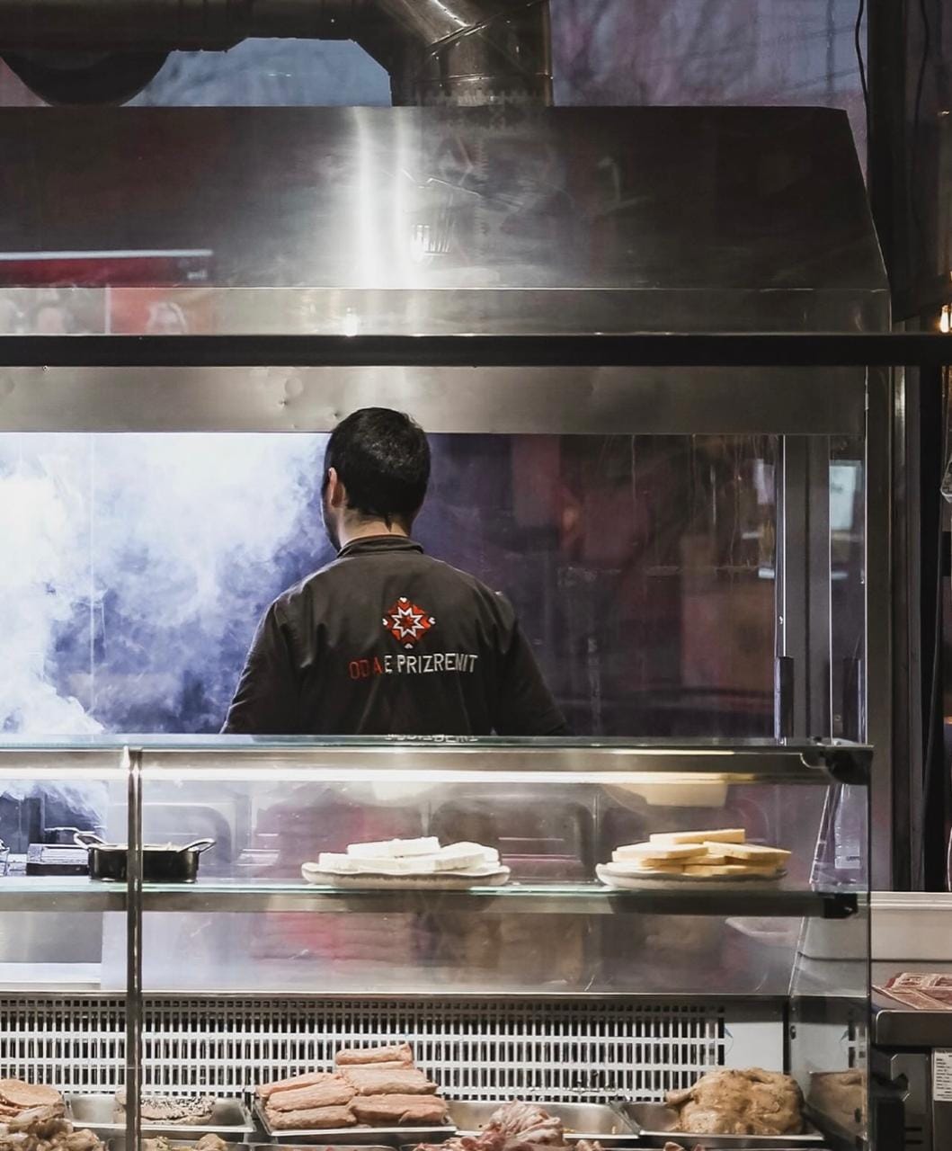 Kuzhinieri i Odës së Prizrenit duke gatuar në zgarë me tym, uniformë profesionale